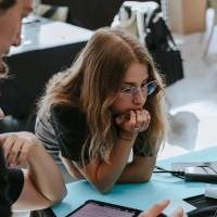 Nerea Panadero Alfonso, sitting at a laptop on a work table, looking at something out of frame.